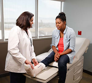 Doctor examining cast on woman's leg.