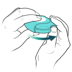 Thumb pushing on thumb grip on side of inhaler.