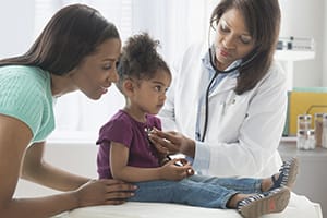 Doctor listening to girl's chest with stethoscope.
